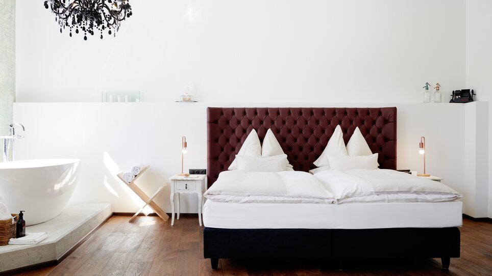 Bedroom in Grand Hôtel Wiesler featuring a double bed and freestanding bathtub. | © Florian Weitzer Hotels & Restaurants