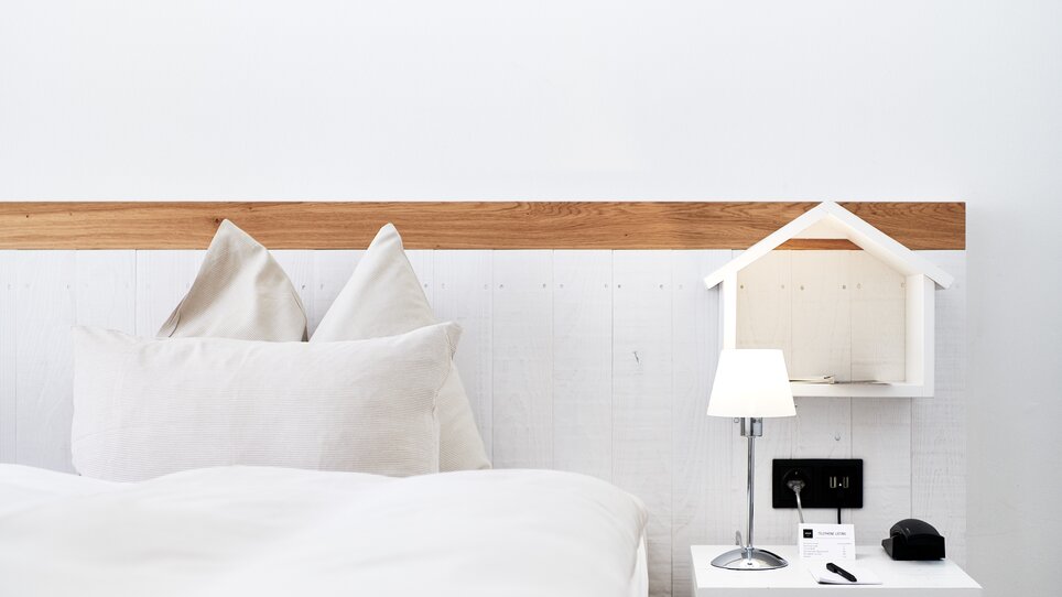 A simple bedroom with bed in Grand Hôtel Wiesler. nightstand, and small lamp. | © Florian Weitzer Hotels & Restaurants