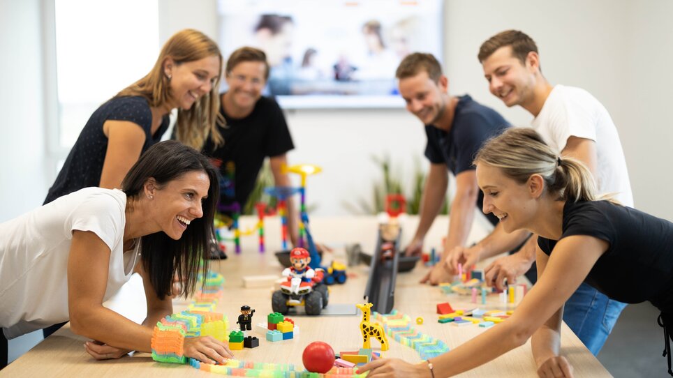 Mitarbeiter spielen mit Bauklötzen in einem modernen Büro. | © Retter Events
