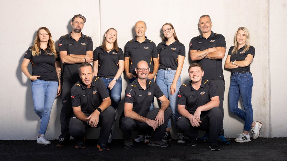 Das Team von Retter Events posiert in schwarzen Poloshirts vor einer Wand. | © Retter Events
