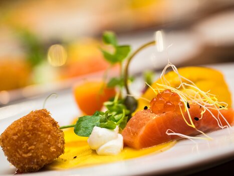 Ein elegantes Gericht mit Lachs, Gemüse und einem knusprigen Ball. | © Revita Gastronomie Ges.m.b.H