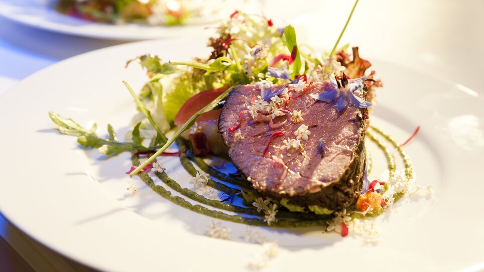 Delicious meat dish on a plate, surrounded by fresh salad. | © Revita Gastronomie