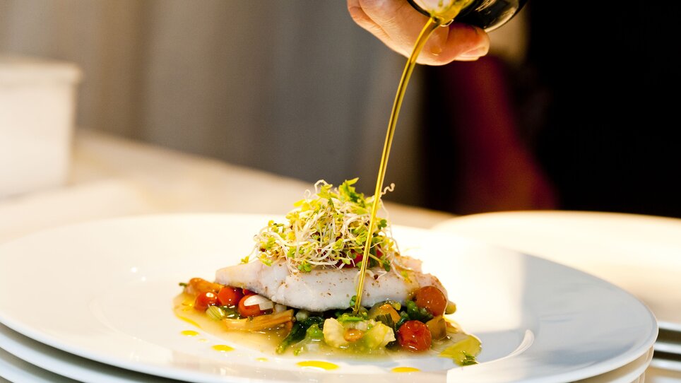 An artistically arranged fish dish being drizzled with oil. | © Revita Gastronomie
