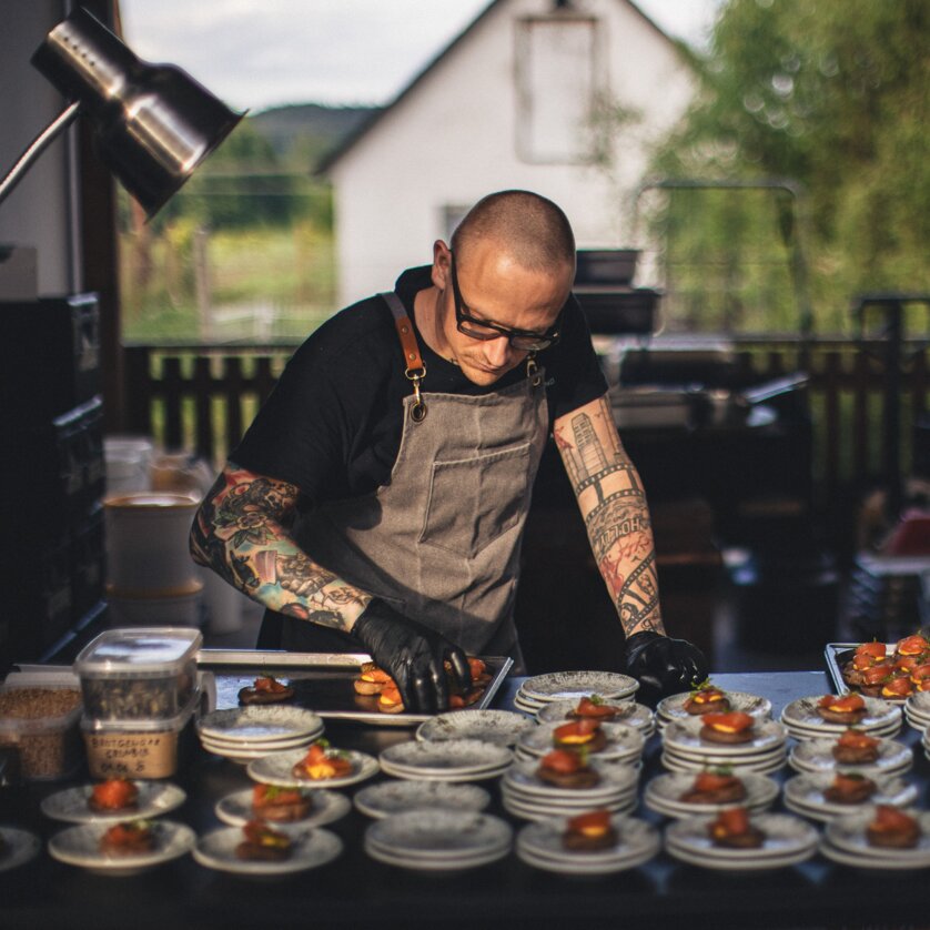 Two chefs garnishing plates in a kitchen with gourmet dishes. | © Alex Rauch