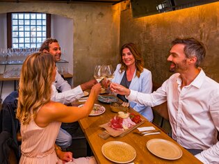 Vier Personen prostend beim Abendessen mit Snacks und Getränken. | © Graz Tourismus - Mias Photoart