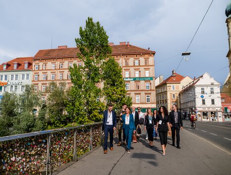 Eine Gruppe von Business-Professionals überquert eine Brücke in Graz. | © Graz Tourismus - Mias Photoart