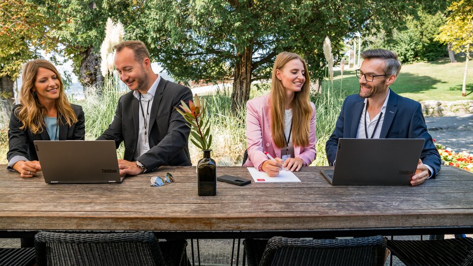 Four people in suits working on laptops outdoors. | © Graz Tourismus - Mias Photoart