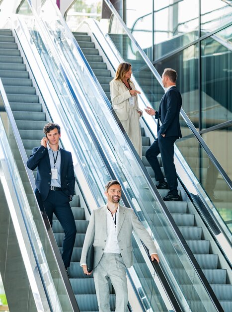 Geschäftsleute in formeller Kleidung interagieren in moderner Architektur. | © Graz Tourismus - Mias Photoart