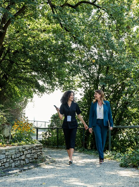 Two women in business attire meeting in a green environment. | © Graz Tourismus - Mias Photoart