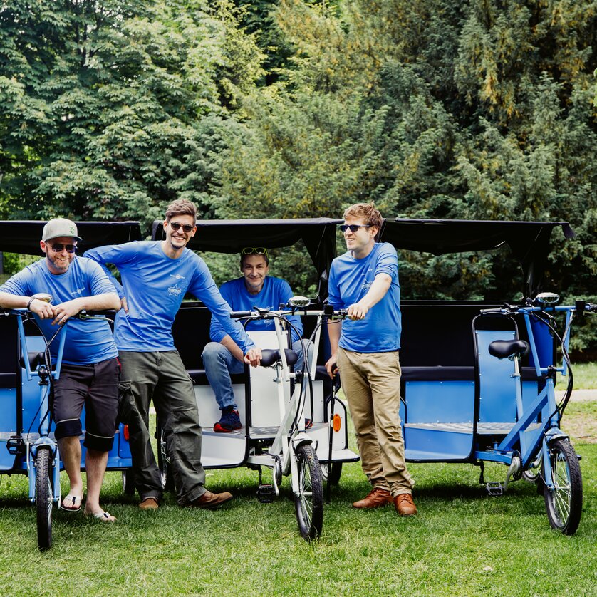 Quattro uomini stanno davanti a risciò nel parco. | © Claudia Plattner