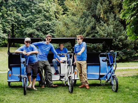 Vier Männer stehen neben Fahrrad-Rikschas im Park in Graz. | © Claudia Plattner
