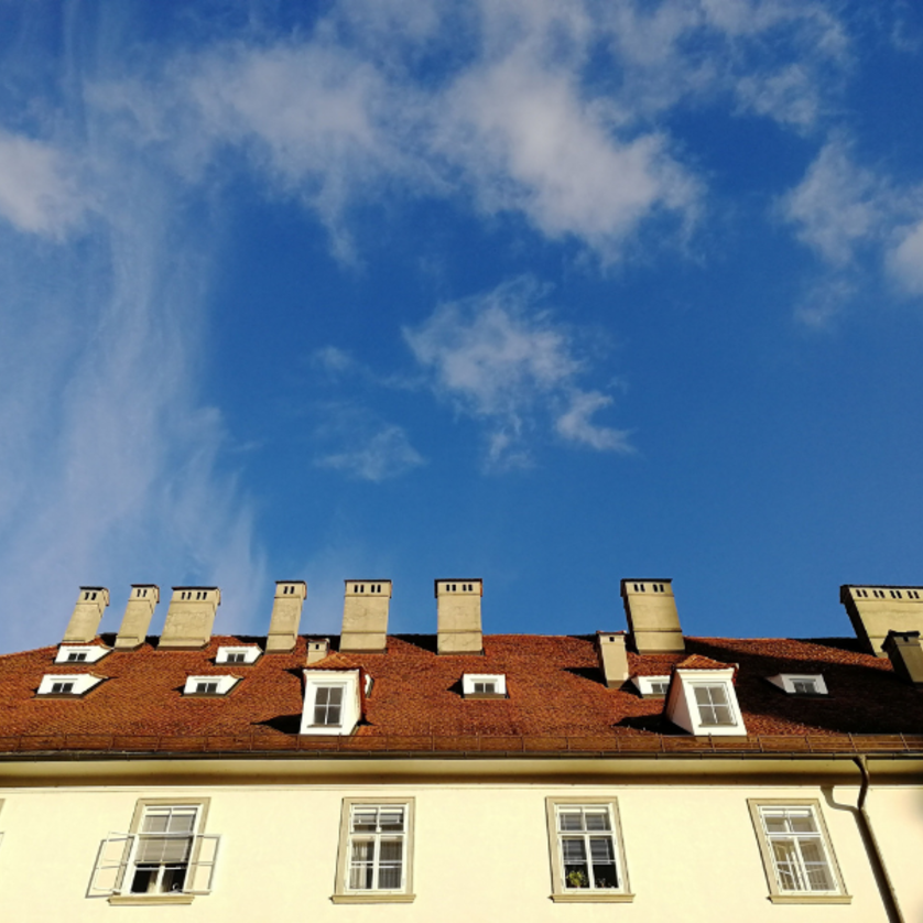 Führung Discover Graz very british | © Ruth Nezmahen Foto Haus mit heller Fassade und vielen Schornsteinen vor blauem Himmel | © Ruth Nezmahen