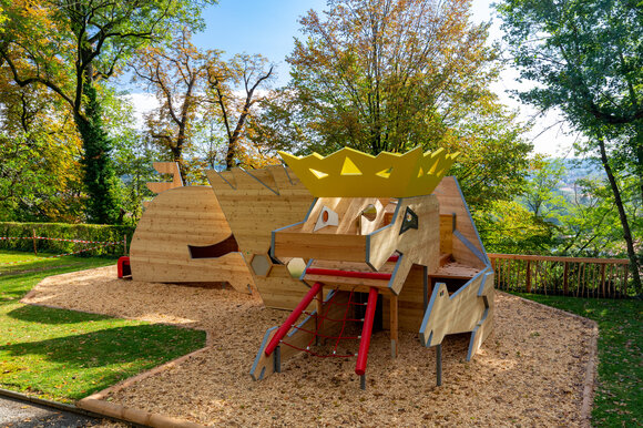 A creative play structure in a park, surrounded by trees and wood chips. | © Graz Tourismus - Harry Schiffer