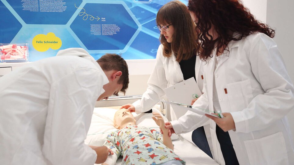 Drei Personen üben an einem medizinischen Übungspuppen im Trainingsraum. | © Universalmuseum Joanneum - J. Kucek