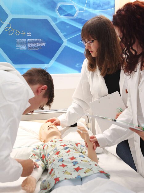 Drei Personen üben an einem medizinischen Übungspuppen im Trainingsraum. | © Universalmuseum Joanneum - J. Kucek