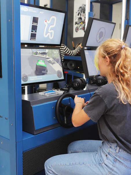Two young people testing a vehicle racing simulator in a modern setting. | © Universalmuseum Joanneum - J. Kucek