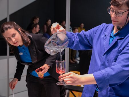 A scientist pours liquid into a glass with colored content. | © Universalmuseum Joanneum - J. Kucek