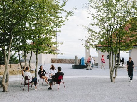 Five people sit outdoors chatting at Graz Museum Schlossberg. | © Sebastian Reiser