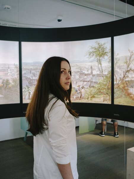 A person stands in front of paintings at Graz Museum Schlossberg. | © Sebastian Reiser