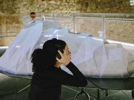 Visitor wearing headphones in an exhibition with a 3D object. | © Sebastian Reiser