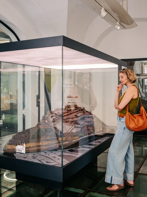 Frau betrachtet ein Modell im Graz Museum. | © Graz Tourismus - Mias Photoart