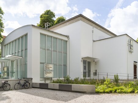 Modern art hall with glass facade and surrounding trees. | © Markus Krottendorfer