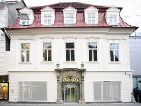 Edificio storico con tetto rosso ed elegante facciata a Graz. | © J.J. Kucek