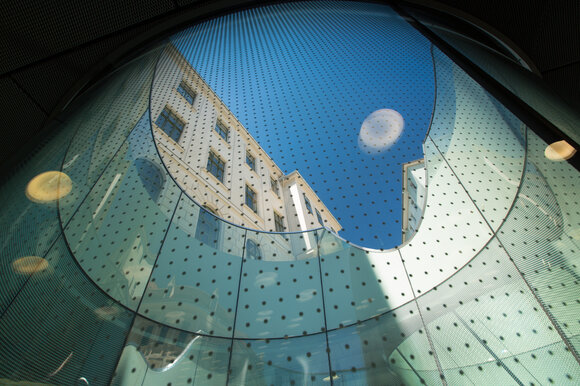 Blick durch einen Glasbogen auf das Joanneumsviertel in Graz. | © Graz Tourismus - Harry Schiffer