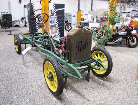 Ein historisches Fahrgestell von Puch mit grünem Rahmen und gelben Rädern in einem Museum. | © Johann Puch Museum