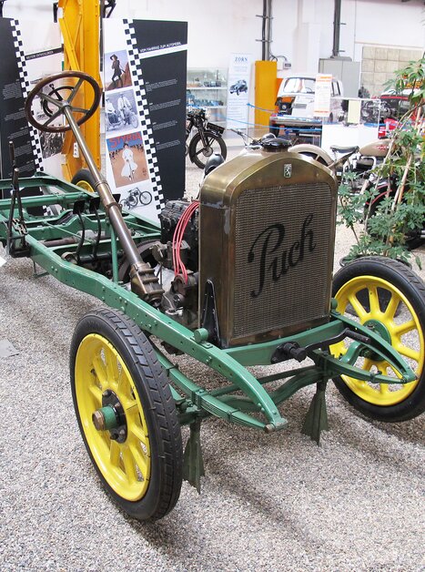 Un telaio storico della Puch con un telaio verde e ruote gialle in un museo. | © Johann Puch Museum