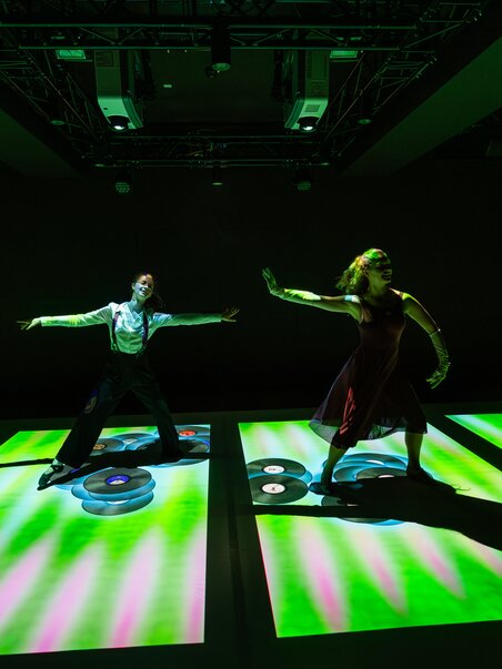 Persone che ballano su proiezioni illuminate di dischi di vinile.