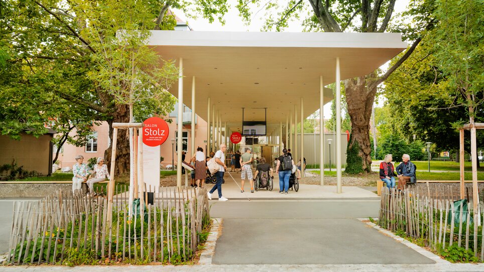 Besucher am Salon Stolz, einem modernen Gebäude in einem Park mit Bäumen. | © Salon Stolz - Stella Kager