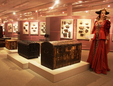 Casse storiche e costumi in un'esposizione. | © Schell Collection