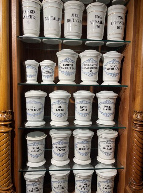 Vasi medici storici esposti nella Farmacia Adler, etichettati. | © Adler Apotheken Museum