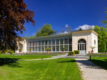 A glass house in Burggarten in Graz, surrounded by greenery and blue skies. | © Graz Tourismus - Harry Schiffer