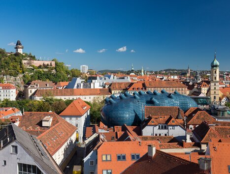 View of the picturesque rooftop landscape of Graz, the Kunsthaus, and the Graz Clock Tower. | © Graz Tourismus - Harry Schiffer