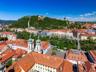 Blick auf Graz mit Schlossberg, Mur und Murinsel und Dachlandschaft im Vordergrund. | © Graz Tourismus - Harry Schiffer