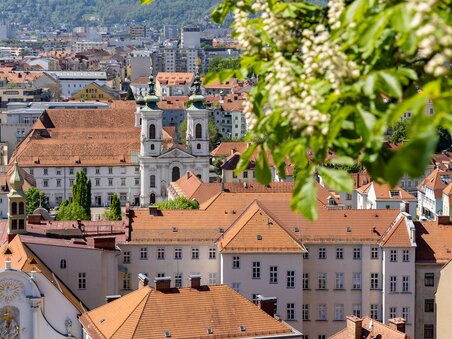 Blick über Graz mit der roten Dachlandschaft und der Mariahilferkirche im Hintergrund. | © Graz Tourismus - Harry Schiffer