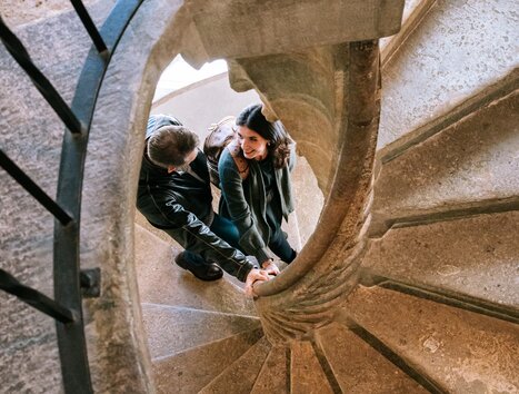 Ein Paar hält sich an der Doppelwendeltreppe in Graz fest. | © Graz Tourismus