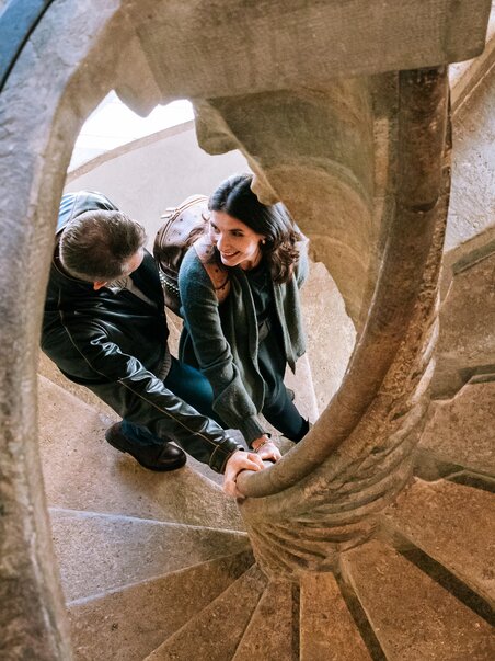 Ein Paar hält sich an der Doppelwendeltreppe in Graz fest. | © Graz Tourismus
