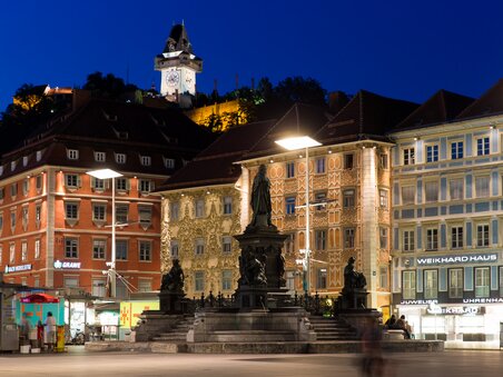 Piazza principale illuminata a Graz con la Torre dell'orologio di Graz sullo sfondo. | © Graz Tourismus - Harry Schiffer