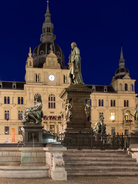 Vista serale del municipio in Hauptplatz a Graz con statue e sfondo storico. | © Graz Tourismus - Harry Schiffer