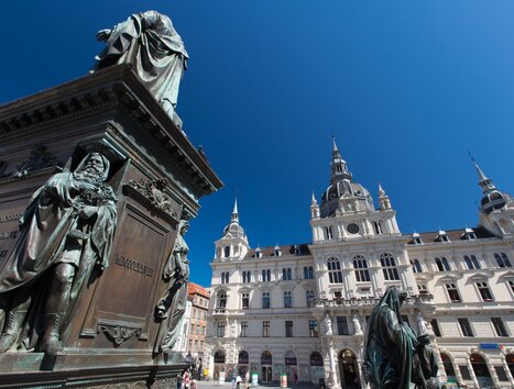 Blick auf das Rathaus am Hauptplatz in Graz mit Statuen im Vordergrund. | © Graz Tourismus - Harry Schiffer