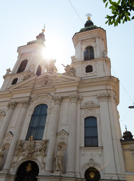 Ansicht einer prächtigen Barockkirche, die von Sonnenlicht umrahmt wird. | © Graz Tourismus - Harry Schiffer
