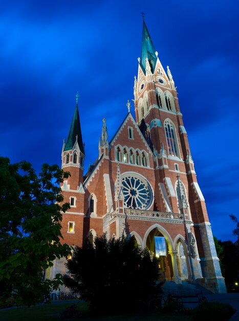 Stilvolle Kirche mit Schnörkeln unter bewölktem Nachthimmel. | © Graz Tourismus - Harry Schiffer