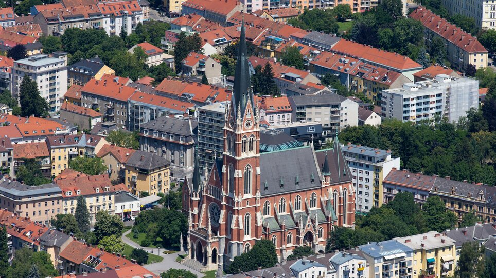 Aussicht über die Stadt Graz mit der Herz-Jesu  Kirche umgeben von Wohngebäuden. | © Graz Tourismus - Harry Schiffer