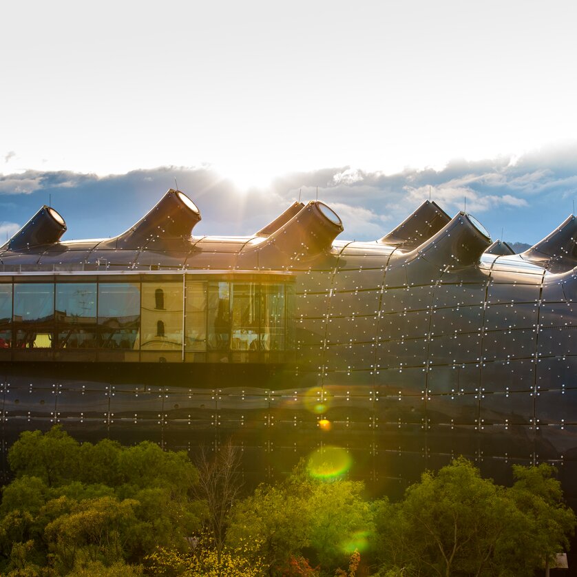 Das Kunsthaus Graz mit einem Kirchturm im Hintergrund. | © Graz Tourismus - Harry Schiffer