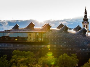 La Kunsthaus Graz con il campanile della chiesa sullo sfondo. | © Graz Tourismus - Harry Schiffer