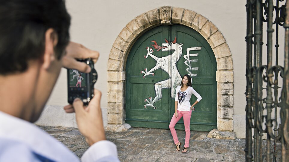 Eine Person wird vor einer bemalten Tür im Landhaushof in Graz fotografiert. | © Graz Tourismus - Toni Muhr