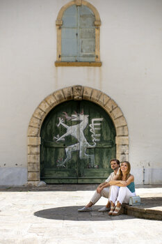 Paar im Landhaushof in Graz, vor einer alten Tür mit grünem Anstrich und dem steirischen Panther. | © Graz Tourismus - Tom Lamm